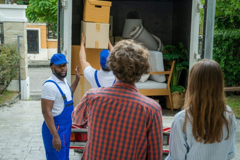 Happy couple with moving boxes at new house,Moving company employee checks boxes in a truck.