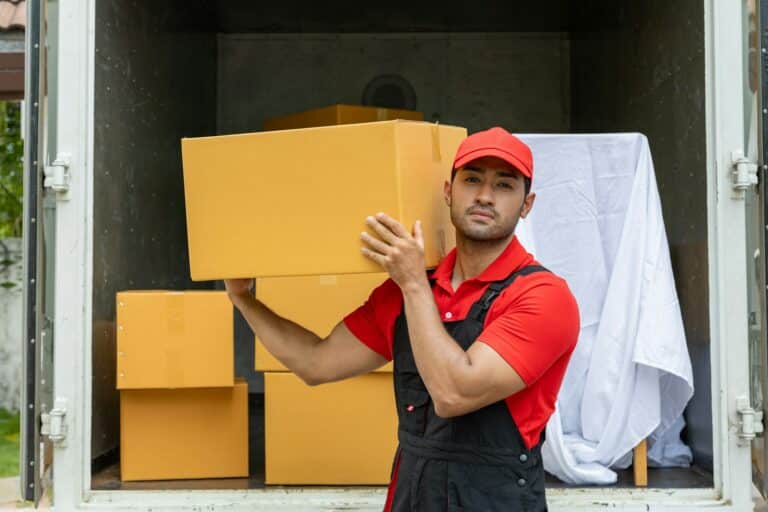Portrait of two movers unloading boxes and furniture from a pickup truck.